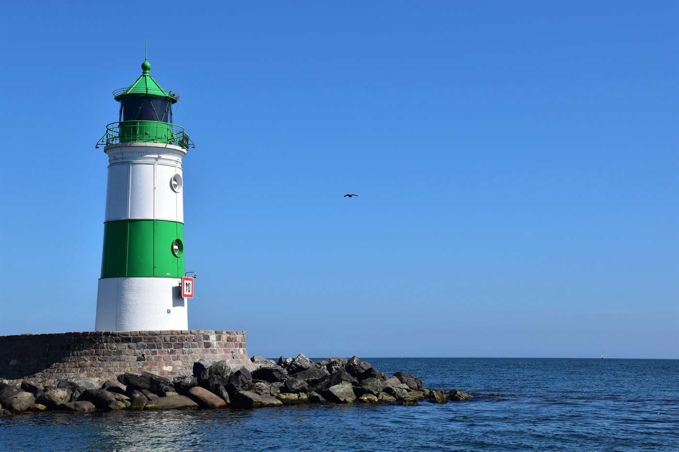 Un phare vert au bord de la mer, symbole d&rsquo;orientation et d&rsquo;accompagnement.